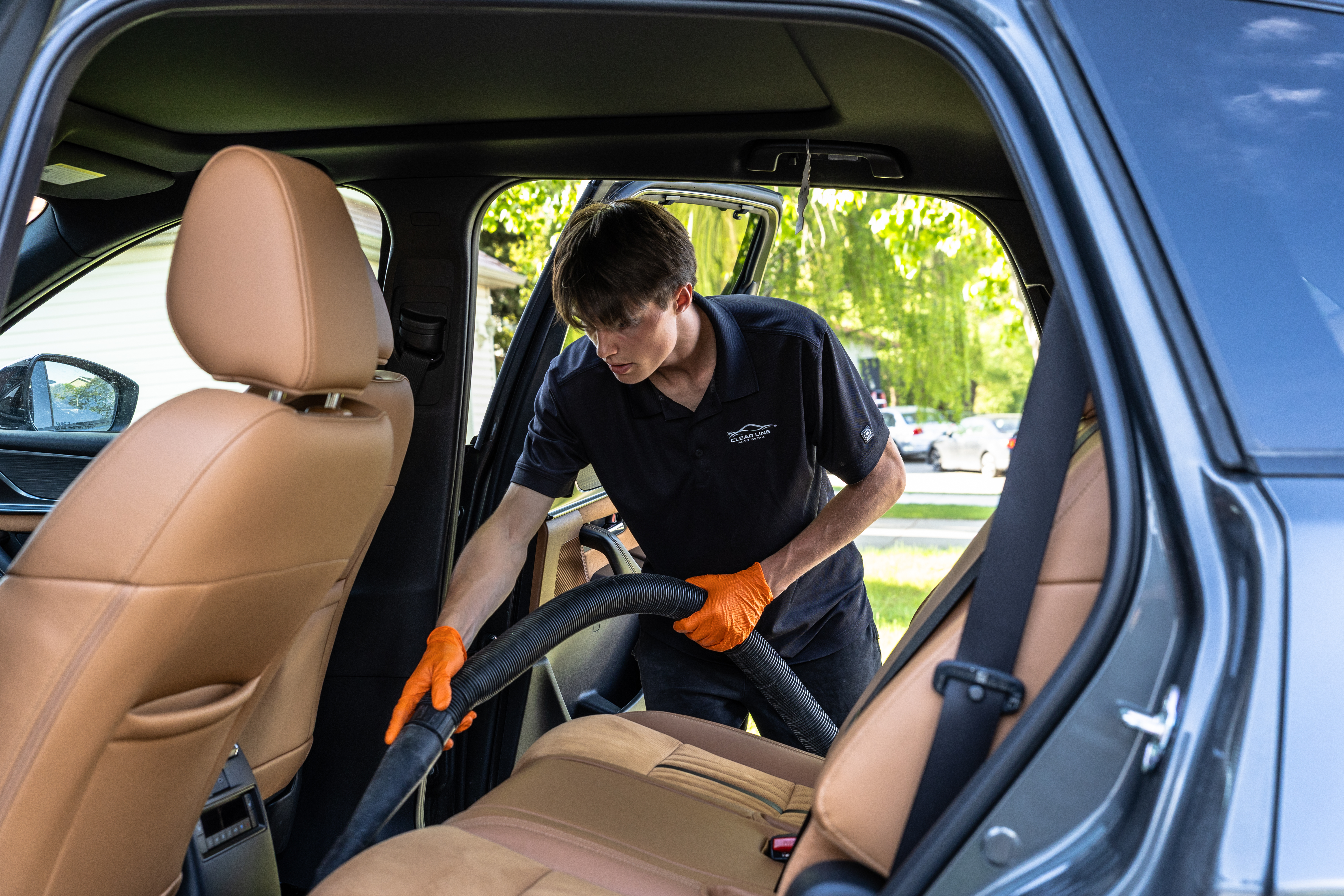 Tyson vacuuming leather seats during an interior detail