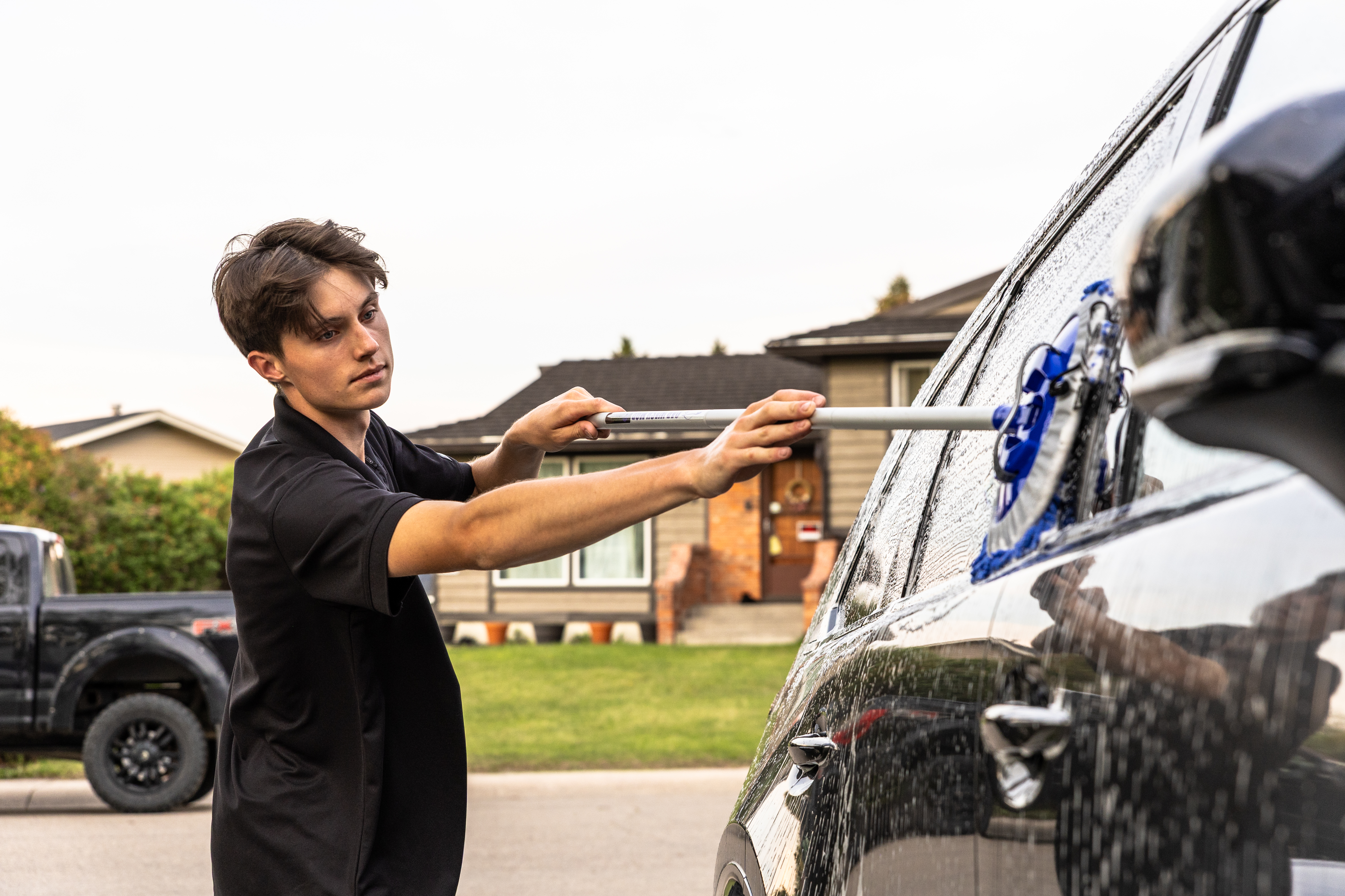 Tyson scrubbing the exterior of a vehicle — Clear Line Auto Detail